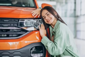 mulher feliz abraçando o carro novo